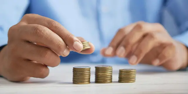 Hands stacking coins into three columns, representing the financial obligations recorded against a property