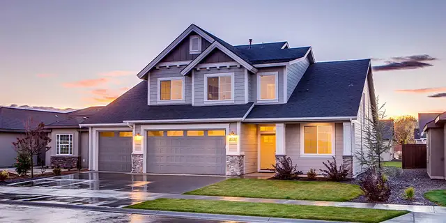 A two-story suburban home at dusk with its windows lit, the kind of marital property a lien search covers